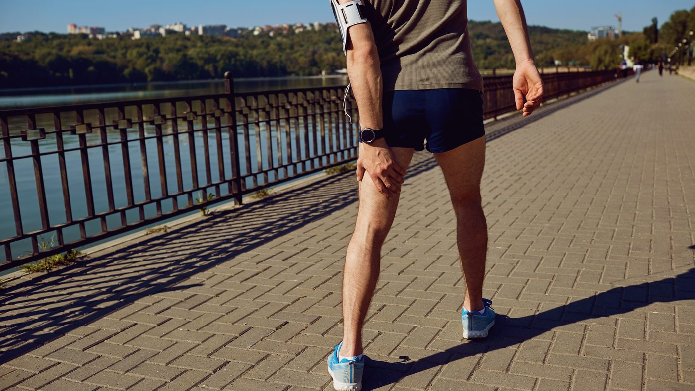 A runner on a waterside promenade holding his knee