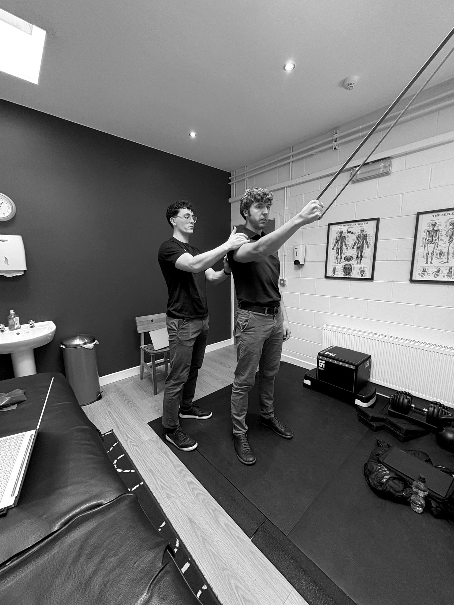 A Reflex therapist guiding a patient's shoulder through a resistance band exercise in the clinic